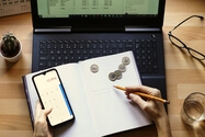 Persona en un escritorio con calculadora, portátil, lápiz y cuaderno